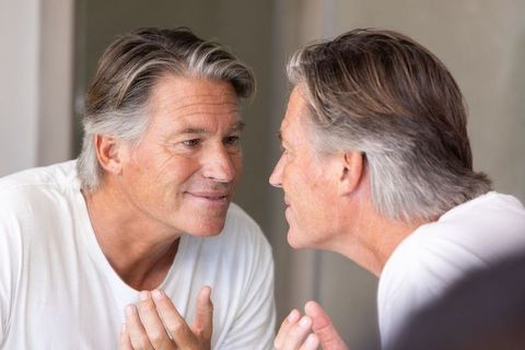 Senior man examining skin in mirror for morning grooming and quiet self-reflection