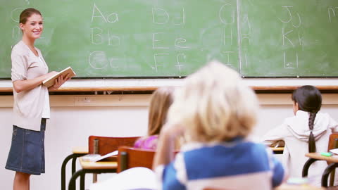 Smiling Teacher Presenting Alphabet Lessons in Classroom