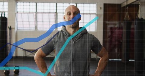 Bald Fitness Trainer Standing in Studio with Performance Chart Overlay and Kettlebells