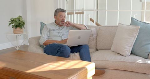 Senior Man Relaxing with Laptop on Couch Enjoying Leisure Time at Home
