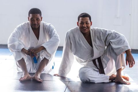 Training partners relax at martial arts gym in white gis
