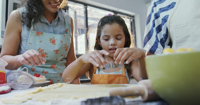 Mother and young daughter in kitchen baking cookies together. Flour and baking tools visible. Ideal for themes related to family bonding, baking activities, parent-child learning, and homemade cooking projects.