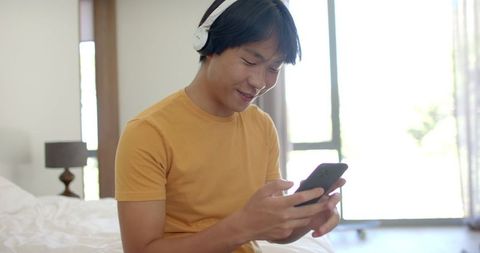 Student Listening to Music with Headphones on Bed