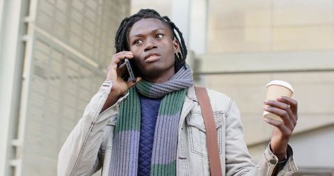 African American Man Talking on Phone Holding Coffee While Waiting Near Office