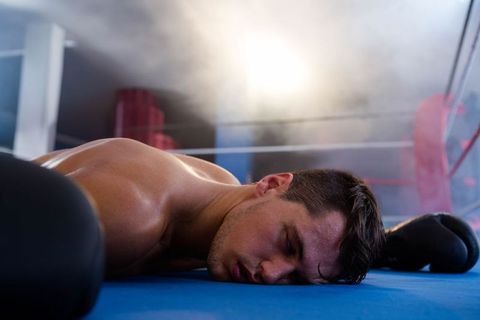 Defeated Boxer Lying in Ring under Arena Lights