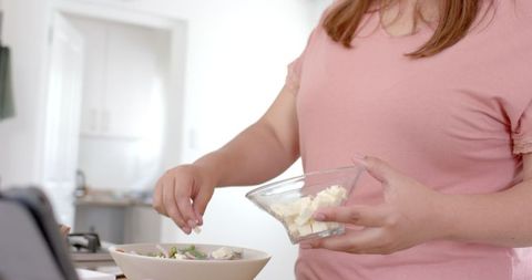 Plus size woman navigating recipe while making fresh salad