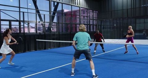 Diverse Doubles Players Engaged in Intense Indoor Padel Match