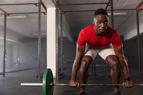 Athletic black man performing deadlifts in gym