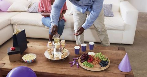 African american family celebrating with cupcakes fruit platter and purple party decor