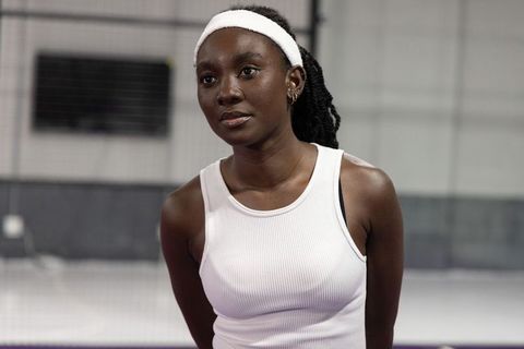 Focused african american athlete pausing on indoor court wearing white headband and tank