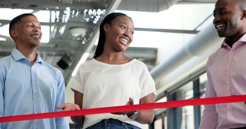 Businesswoman cutting red ribbon at business event