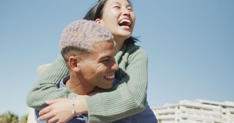Diverse Couple Laughing on Sunny Promenade by Sea