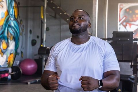African american man working out in gym wearing white shirt and smartwatch, focused