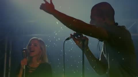 Dynamic Live Duet: Male Lead Singing into Mic with Female Vocalist Duetting in Backlit Fog