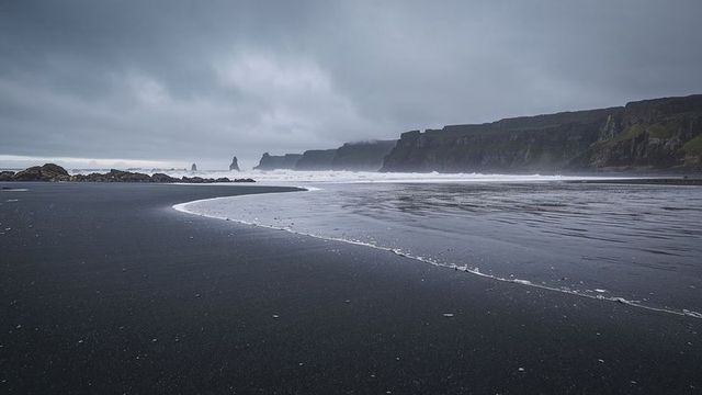 Moody Black Sand Beach with Basalt Cliff and Foam Shoreline