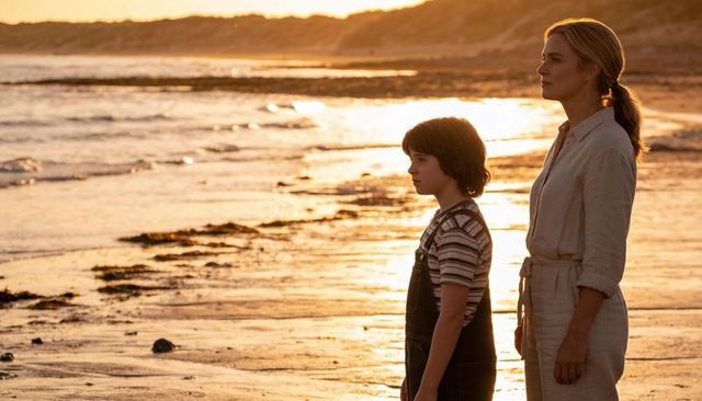 Mother and son standing on golden hour beach overlooking tidal pools and distant horizon