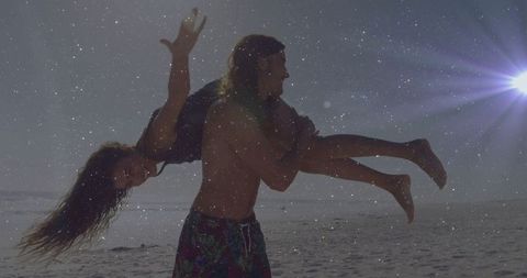 Energetic beach fun with couple under sunlit sky