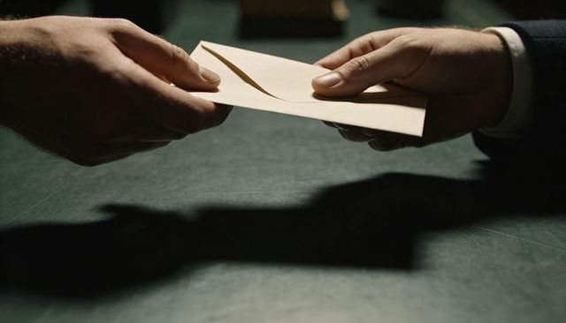 Hands Exchanging Sealed Envelope Over Green Desk Conveying Confidential Business Transfer