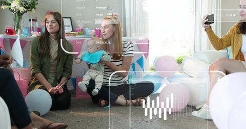 Women holding baby at pastel baby shower celebrating with balloons, cake and gifts