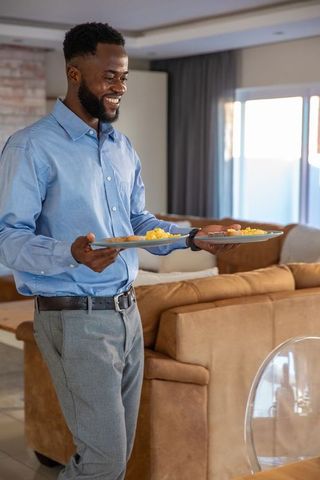 Smiling man serving breakfast moving through modern living room