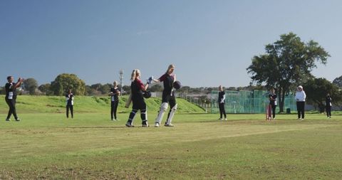 Female Cricket Player Celebrated by Teammates on Sunny Field
