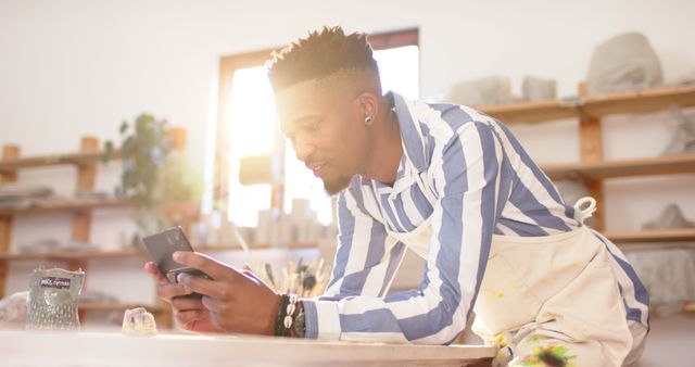 Young Man in Pottery Studio Using Smartphone in Sunlit Room - Download Free Stock Images Pikwizard.com