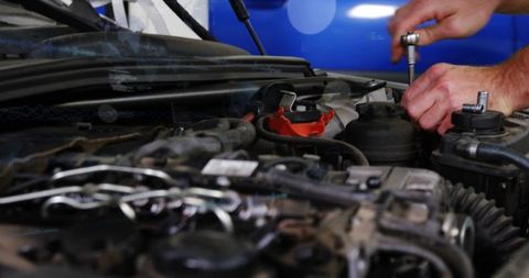 Mechanic tightening engine components with socket wrench in car repair workshop closeup