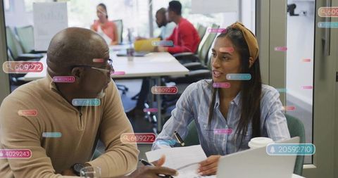 Multigenerational colleagues collaborating over laptop and documents in modern office meeting