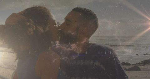 Couple kissing on rocky beach at sunset with cosmic nebula overlay and lens flare