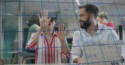 Woman testing vr headset with colleague collaborating on virtual data grid in office