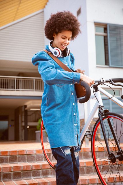 Biracial female business creative wearing headphone arriving with bike outside workplace. independent creative business people working at a modern office.