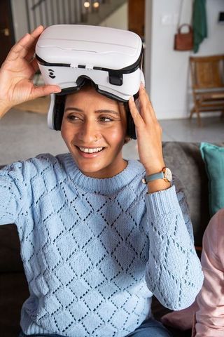 Smiling indian woman interacting with vr headset at home