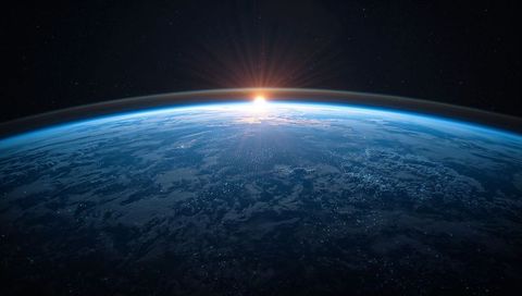 Sun Rising Over Earth from Low Orbit Showing Blue Atmospheric Halo and City Lights