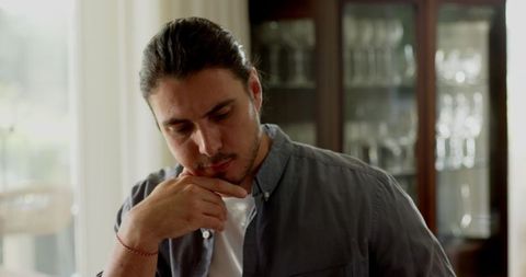 Man intently writing notes at home by sunlit window