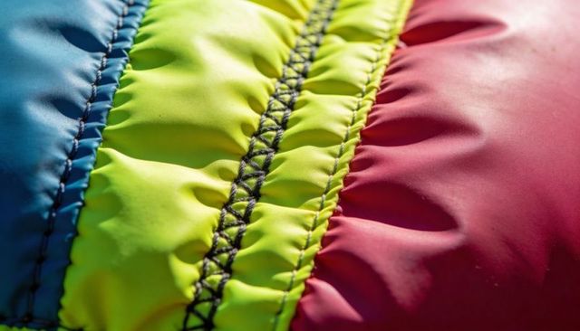 Neon quilted fabric close-up showing zigzag stitch and padded colorblock panels