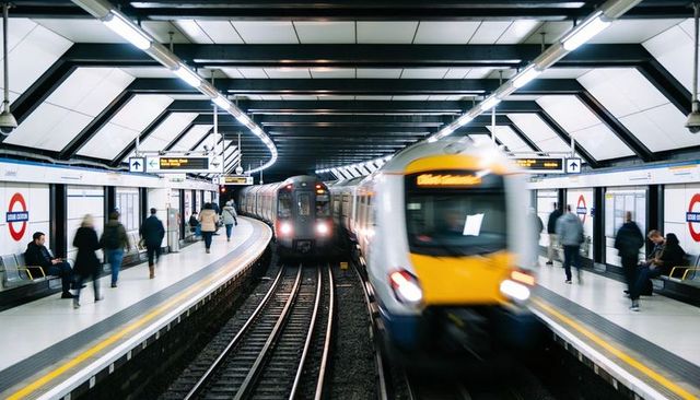Yellow commuter train entering underground station with motion blur and busy platform