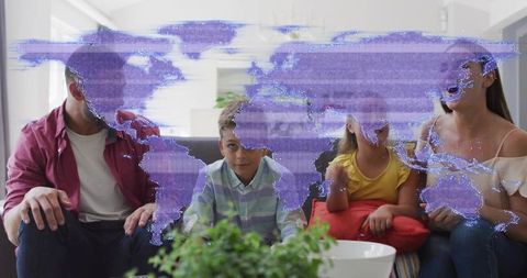 Family watching digital world map hologram overlay while sitting on sofa in living room
