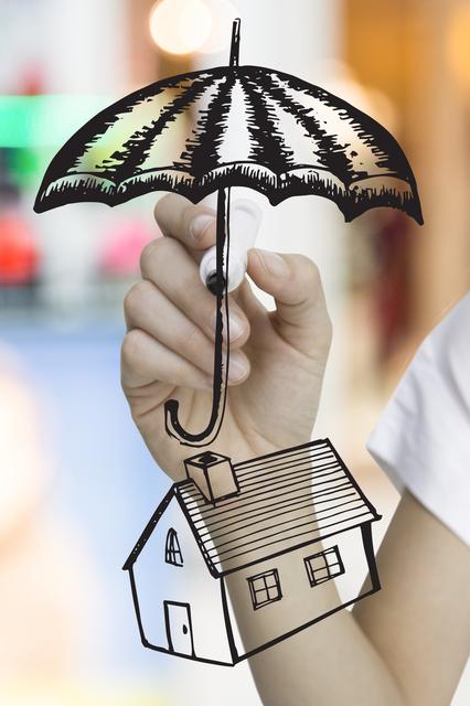 composite of hand drawing umbrella over house graphic