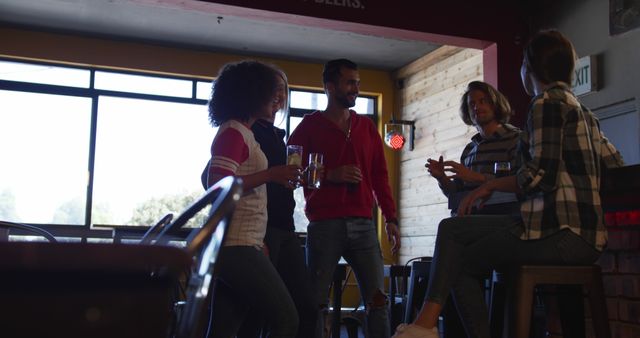 Young adults in casual attire socializing in a modern cafe. They are gathered around a high table, chatting and enjoying their drinks in a relaxed and cheerful atmosphere. Great for promoting social interaction, friendship, leisure activities, and modern lifestyle concepts.