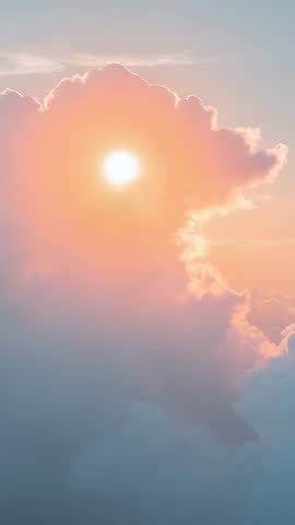 Vertical video of sun emerging behind cumulus cloud casting warm pastel sunrise glow
