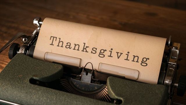 Vintage typewriter typing thanksgiving on aged paper rustic wood table close-up