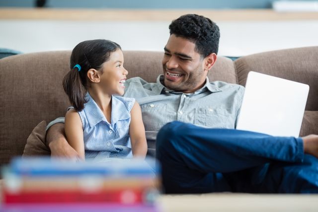 Father and daughter interacting on sofa in living room at home