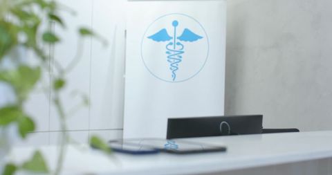 Modern medical reception desk reflecting blue caduceus emblem on glossy white counter