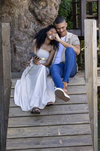 Couple sharing tender moment on rustic wooden steps holding pale yellow rose