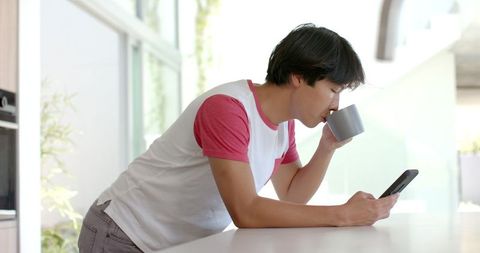Young Asian Student Drinking Coffee While Using Smartphone in Bright Room - Download Free Stock Images Pikwizard.com