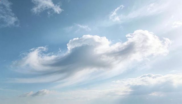 Sunlit Billowing Cloud Drifting Across Blue Sky with Wispy Cirrus and Serene Light