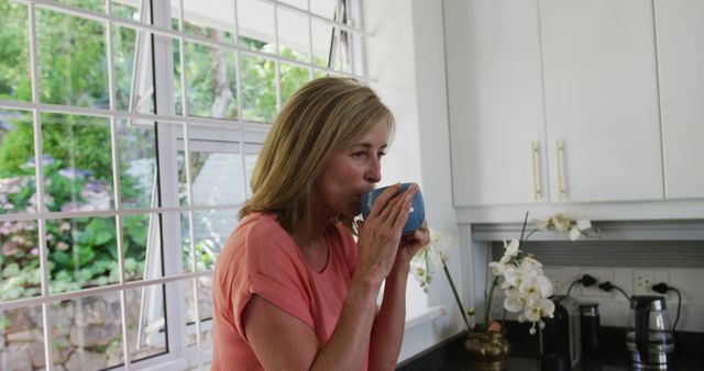 Caucasian senior woman standing in kitchen at home drinking cup of coffee. staying at home in isolation during quarantine lockdown.