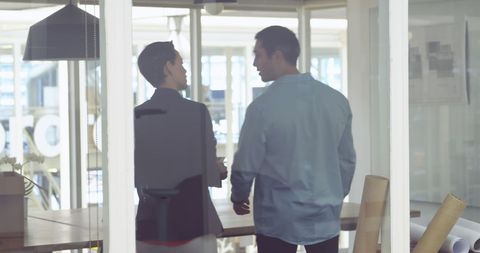 Business Professionals Engaged in Office Discussion Through Glass Walls