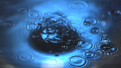 Blue Rippling Water with Drops Creating Circular Waves