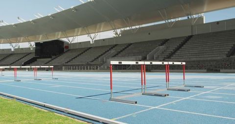 Featuring Red-and-White Hurdles on Blue Track in Empty Stadium for Athletics Training